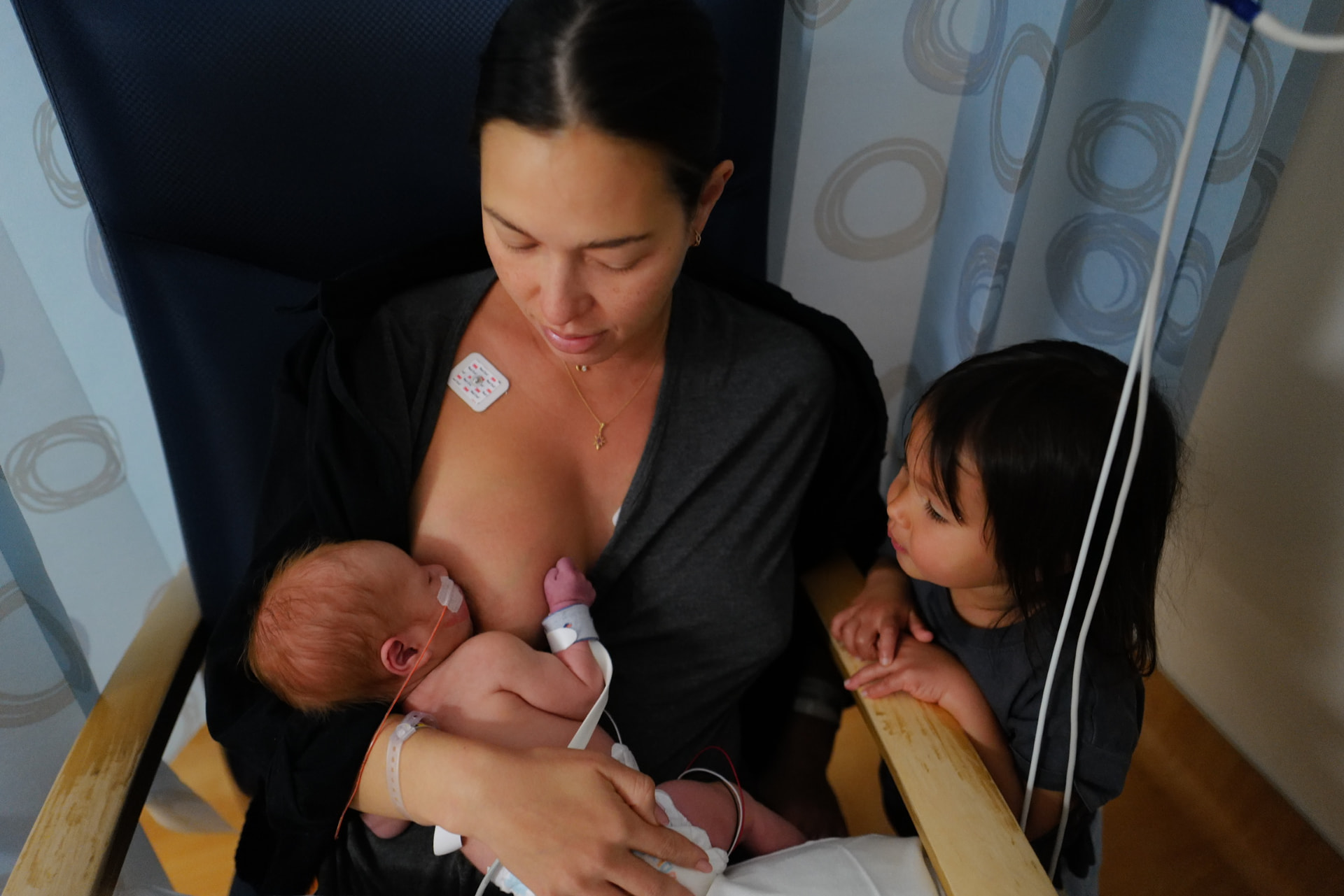 Liv Golding nursing her newborn while seated in a hospital chair, her daughter resting beside her